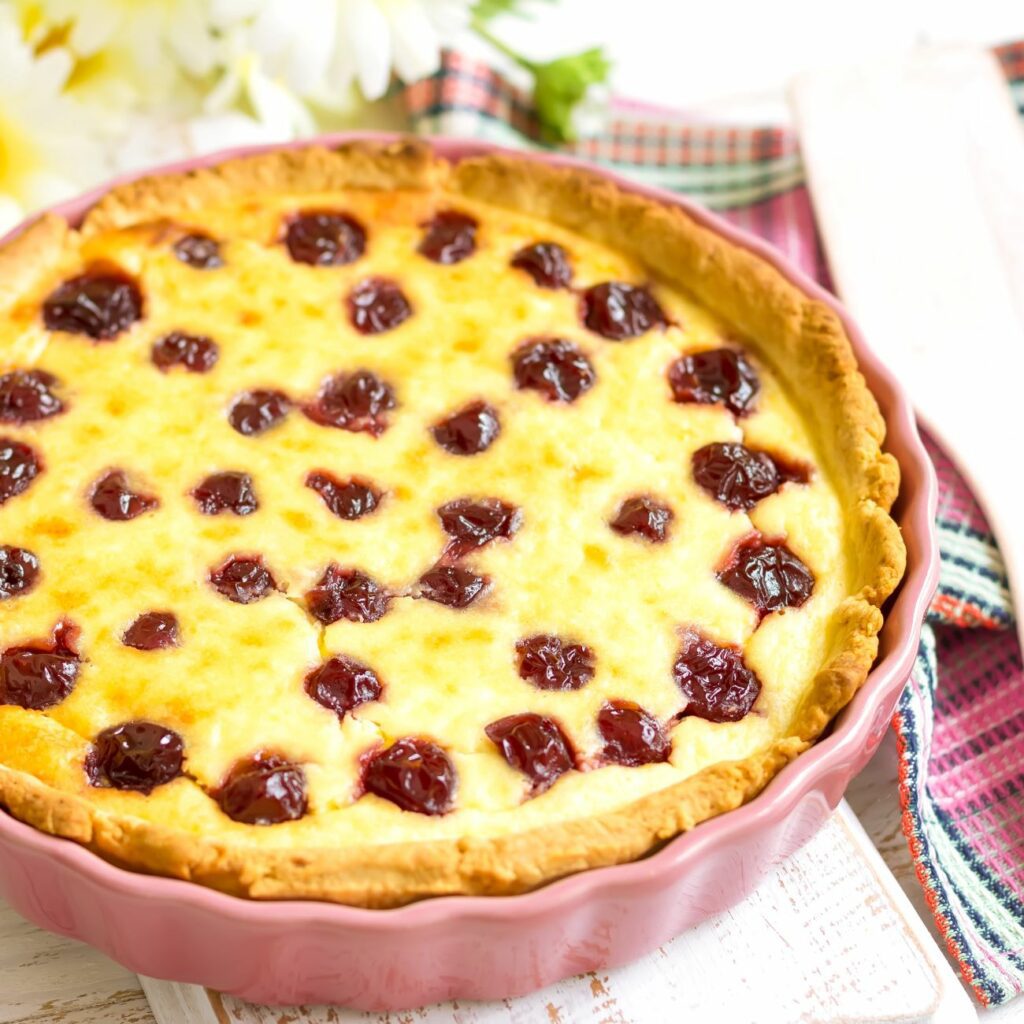 Kirschkuchen mit Pudding und Schmand auf einer Tortenplatte serviert
