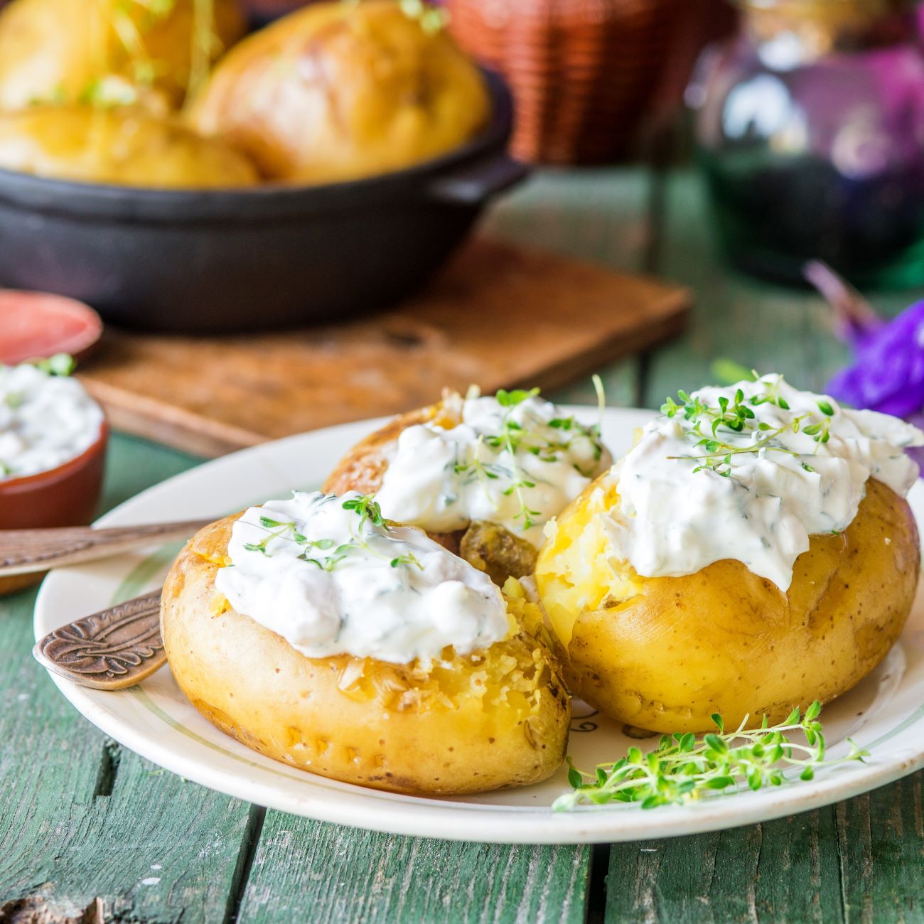 Backkartoffeln werden mit Sour Cream auf einem weißen Teller serviert