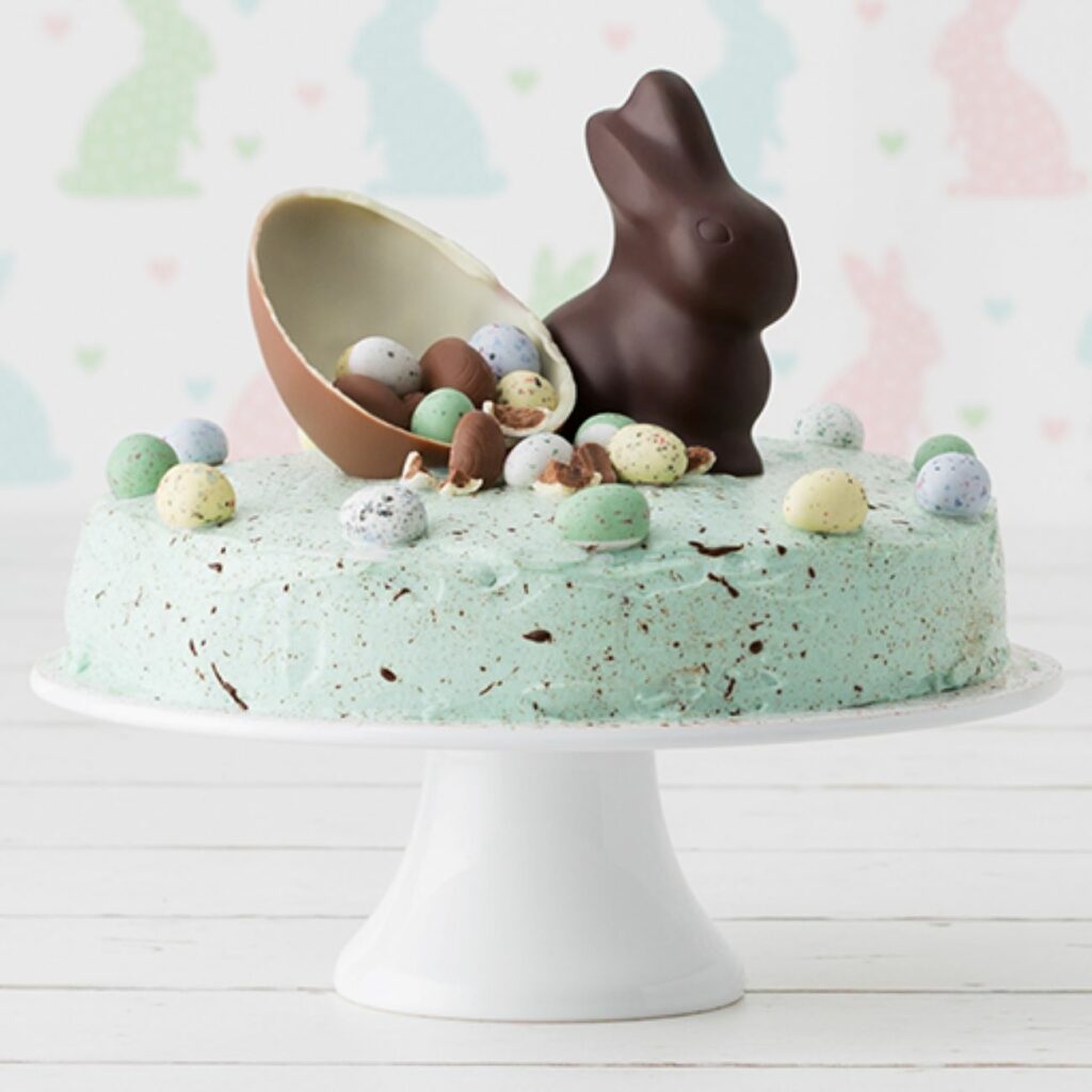 Ostertorte mit Osterhasen wird auf einer Tortenplatte gezeigt.