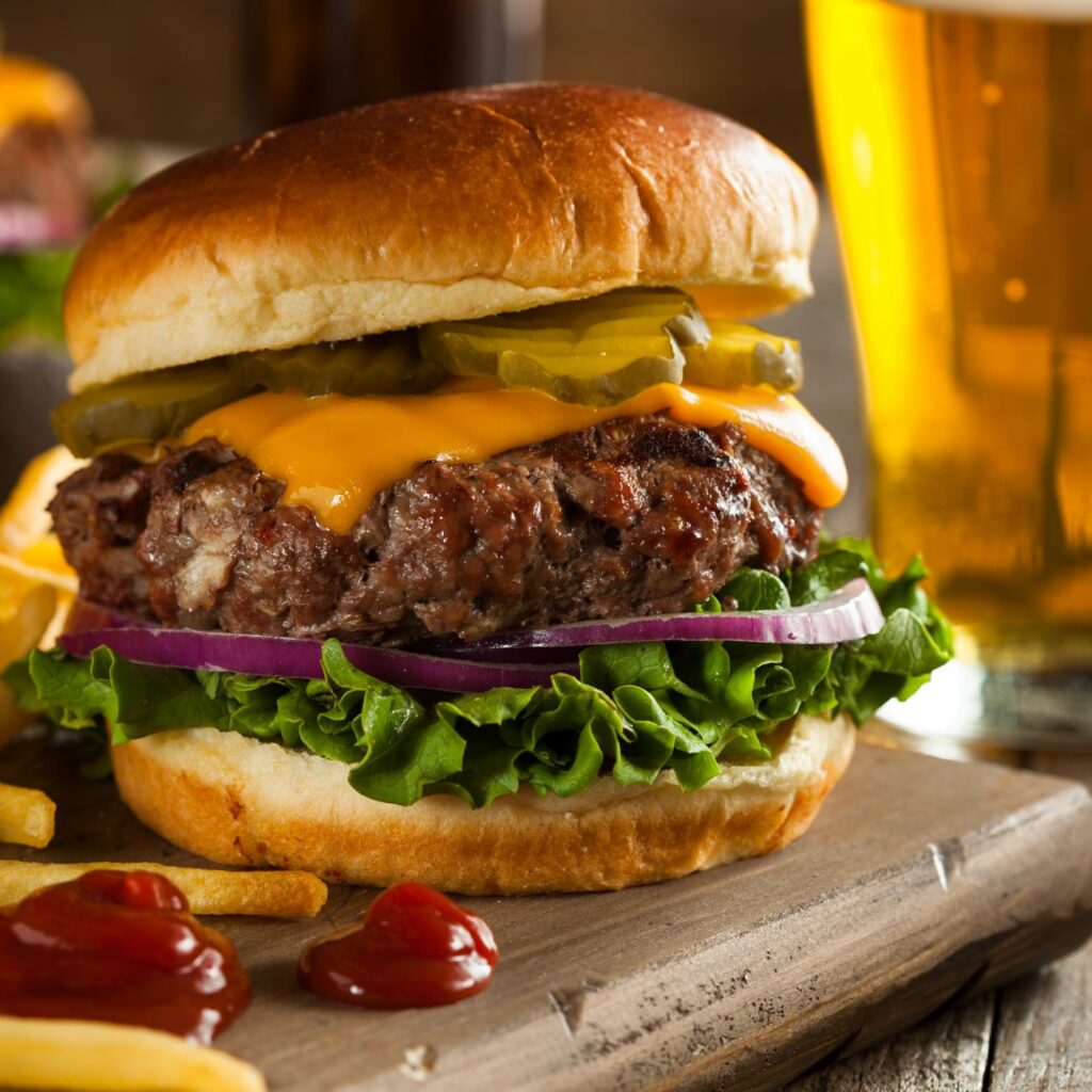Cheeseburger wird nah und mit Pommes als Beilage gezeigt.