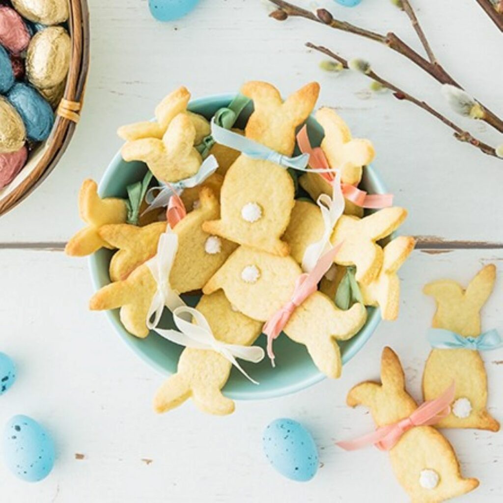 Osterhasen-Plätzchen werden in einer Schüssel und mit osterlicher Deko präsentiert.