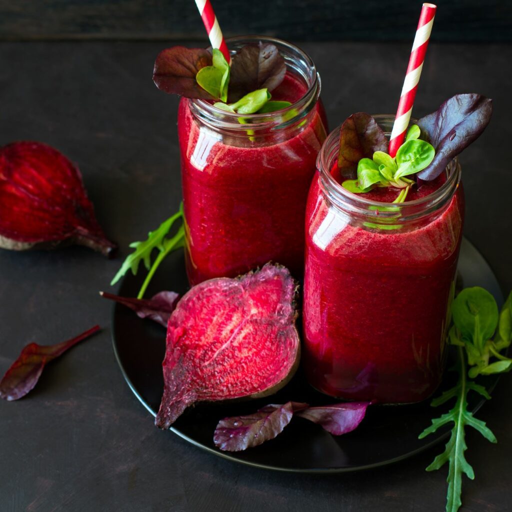 Rote Bete Smoothie wird in zwei Gläsern mit Strohhalm serviert.