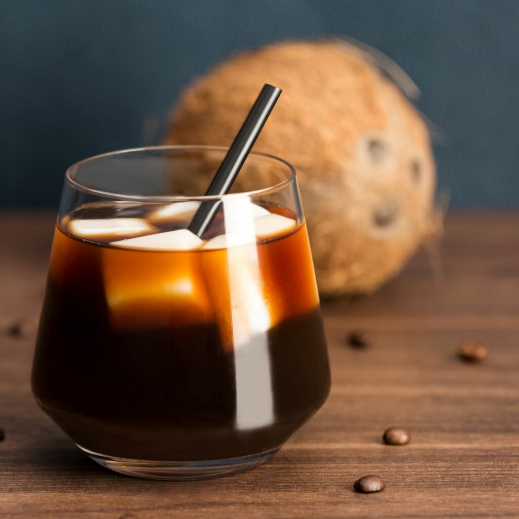 Coffee on Ice s kostkami ledu z kokosového mléka se podává ve sklenici s brčkem.