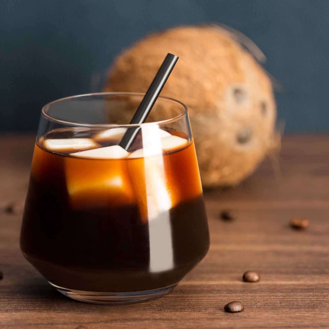 Coffe on Ice mit Kokosmilch-Eiswürfeln wird mit Strohhalm im Glas serviert.