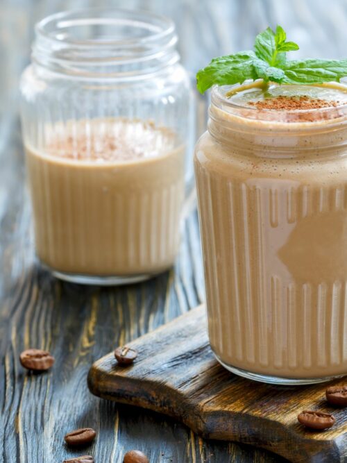 Kaffee-Smoothie wird in einem großen Glas getoppt mit Kakao präsentiert.