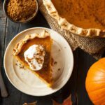 Pumpkin Pie wird mit zimtiger Sahne auf einem herbstlichen Untergrund serviert.