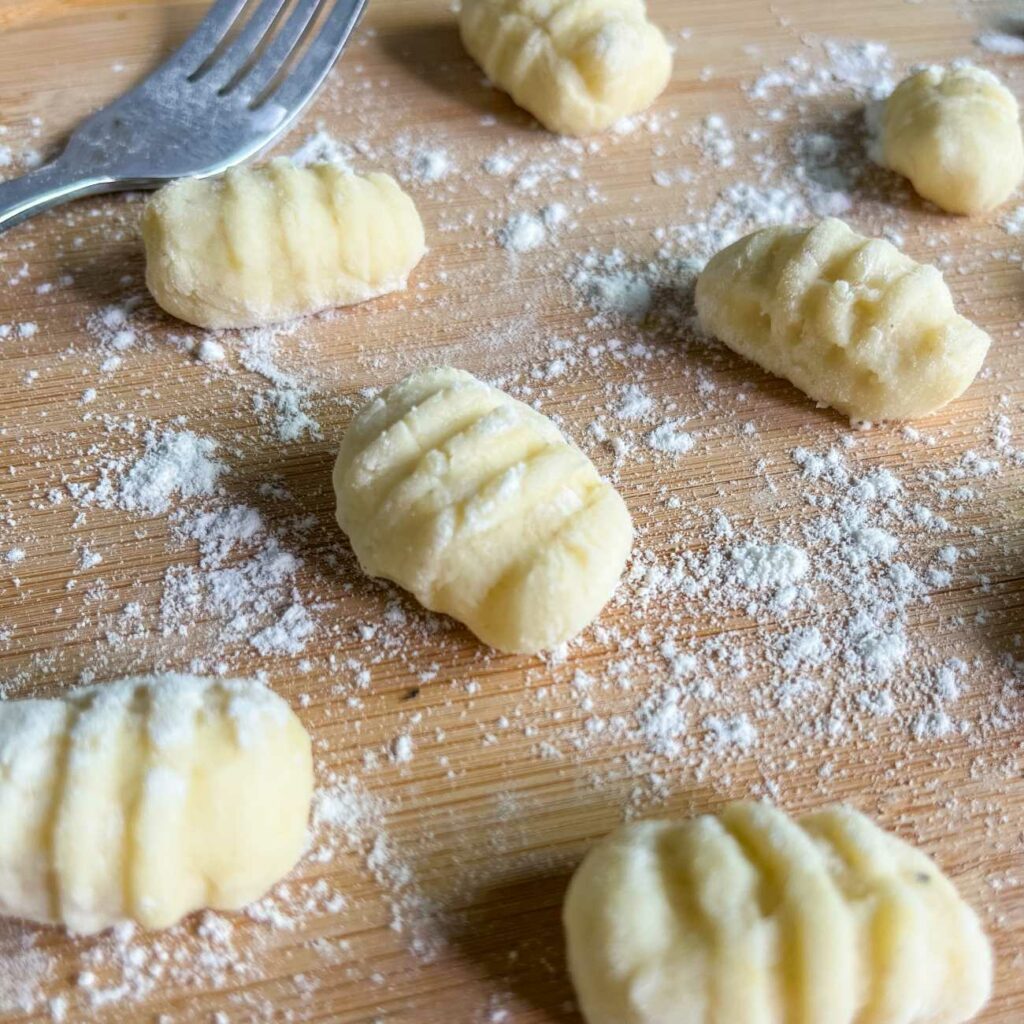 Gnocchi selber machen: Gnocchi werden auf einem bemehlten Holzbrett mit einer Gabel gezeigt.