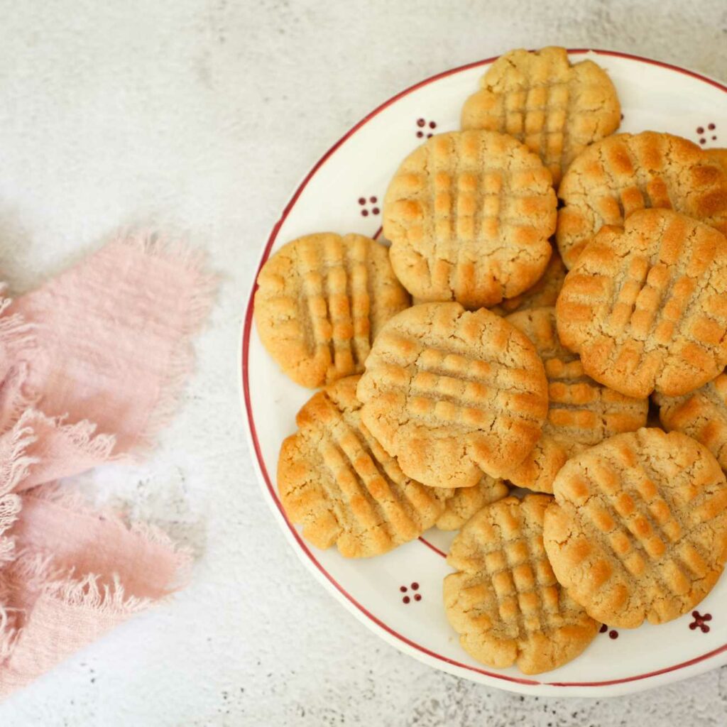 Sušenky z arašídového másla jsou na malém talířku s růžovým ručníkem.