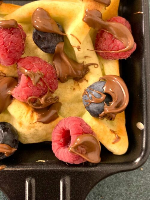 Crêpe-Raclette wird mit Beeren und Nutella im Pfännchen gezeigt.
