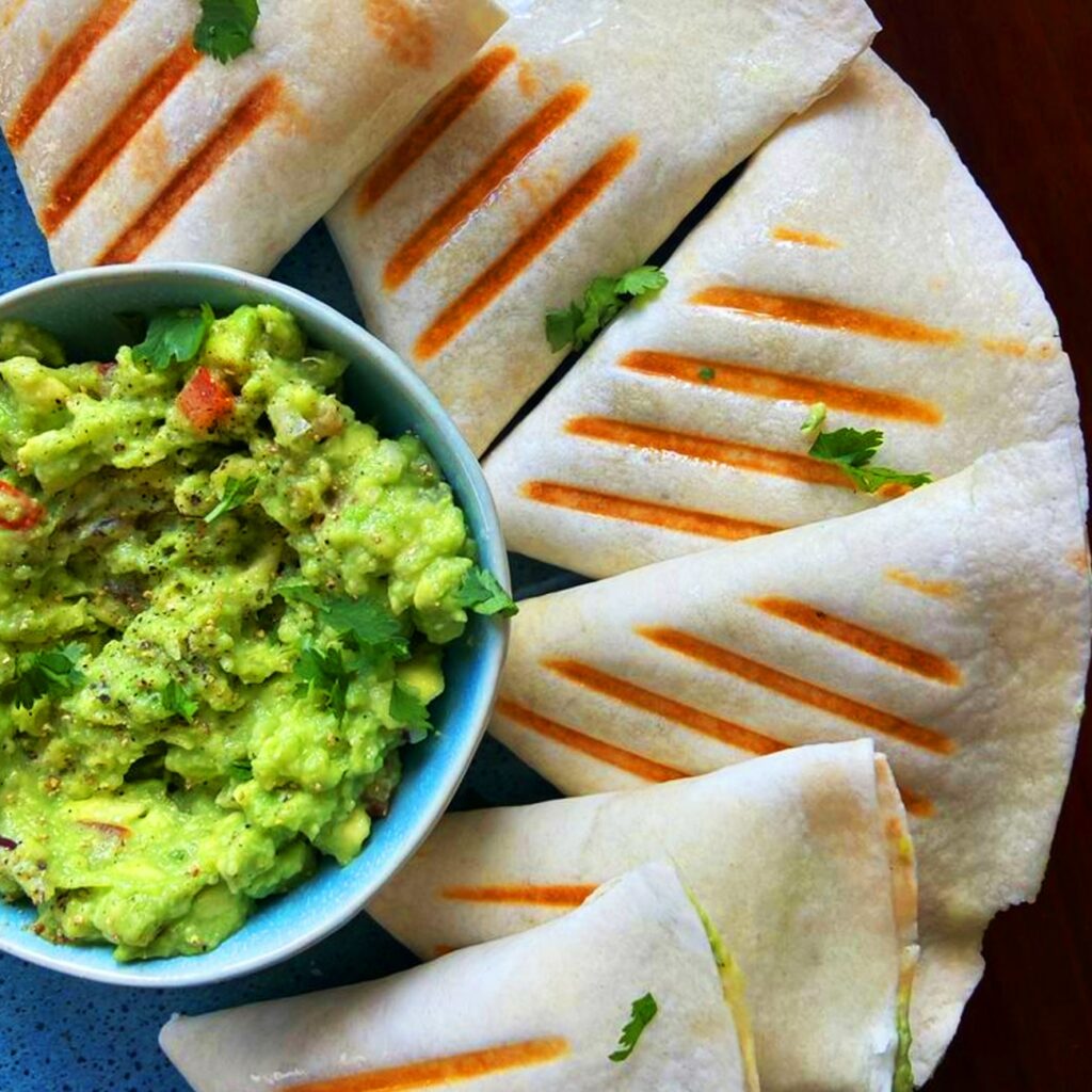 Tortillové kapsy s guacamole jsou zobrazeny na talíři s guacamole.