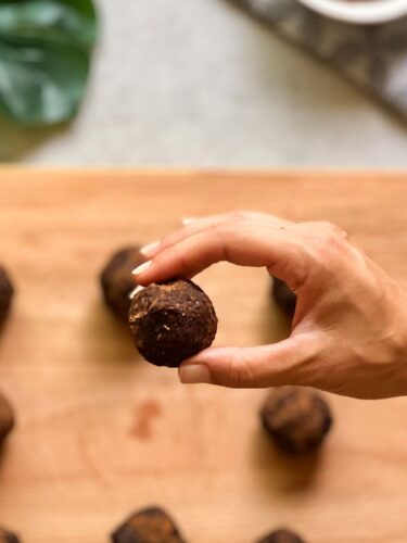 Brownie Bites werden auf einem Brett gezeigt. Einer wird in der Hand in den Fokus gerückt.